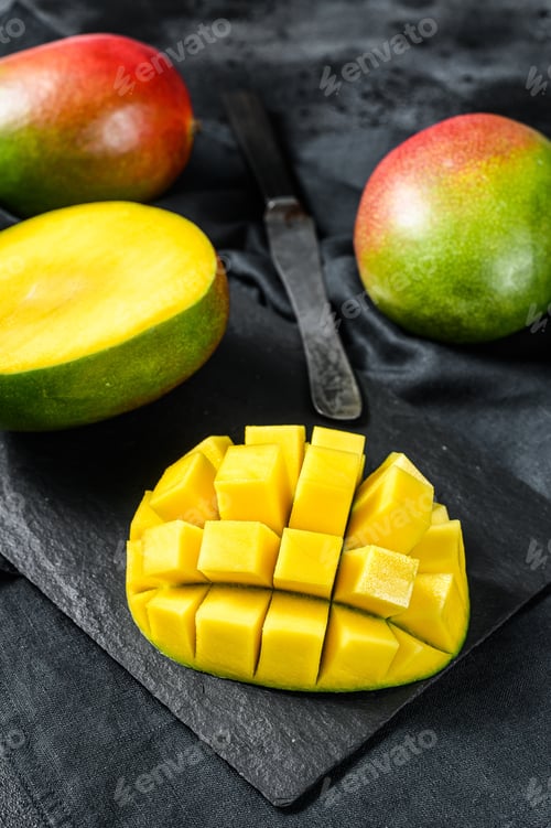 Preview: Ripe mango fruit, cut into cubes. Black background. Top view