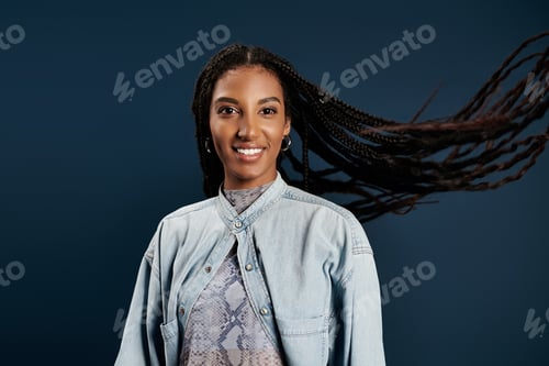 Preview: Stylish young woman with flowing hair poses gracefully against a striking blue backdrop