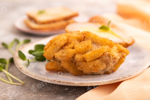 Preview: Chicken schnitzel on blue plate with microgreen on brown concrete, selective focus