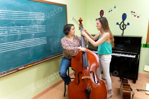 Preview: Music teacher helping student playing contrabass in classroom