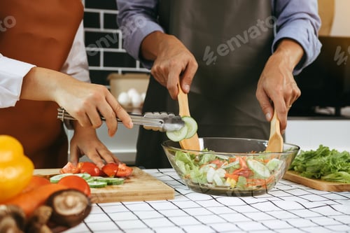 Preview: Asian couple preparing healthy salad in the kitchen.