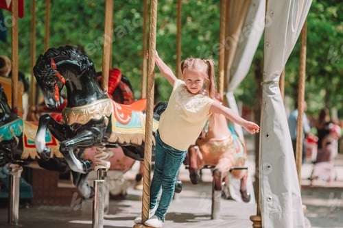 Preview: Adorable little girl near the carousel outdoors