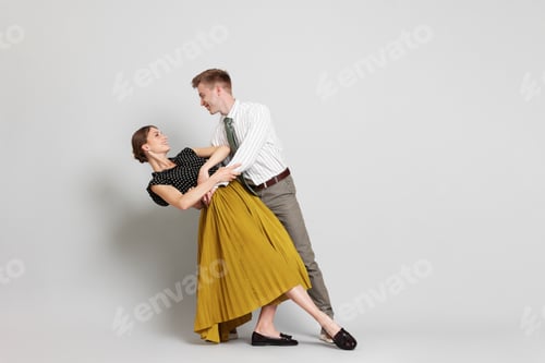 Preview: Happy couple in retro outfits dancing on light grey background, space for text