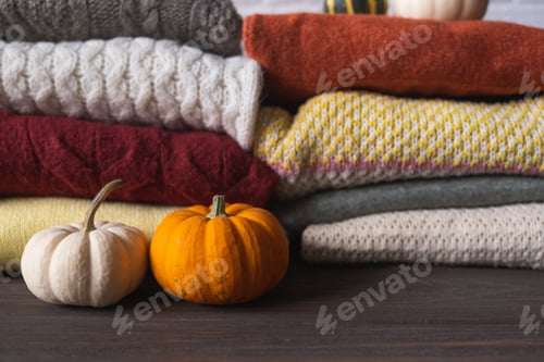 Preview: Autumn background with a variety of wool knitted sweaters and pumpkins