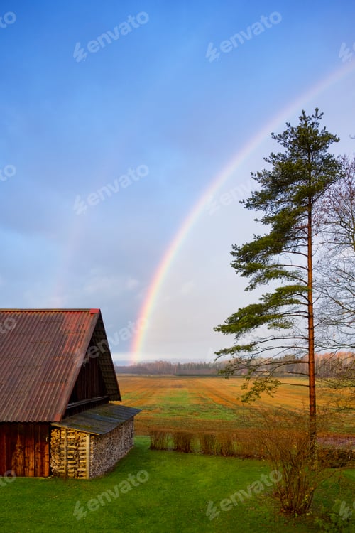 Preview: Rural scene, a rainbow in the sky over a barn, after rain.