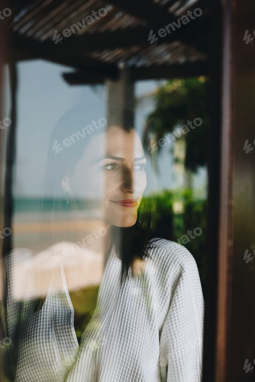 Preview: Woman looking out her hotel room window