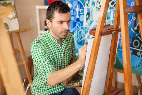 Preview: Portrait Of A Young Hispanic Artist Focused On His Latest Painting On His Studio