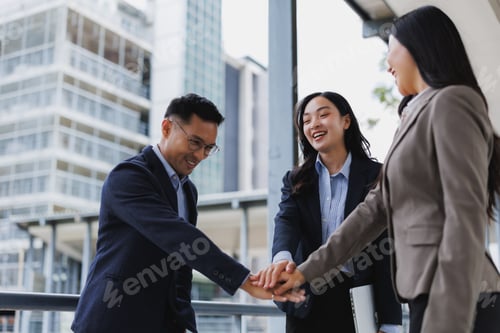 Preview: Happy business team joining hands, celebrating success in modern office building