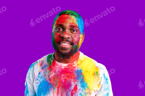 Preview: latin brazilian male in white cotton t-shirt with colorful paint of face laughing studio