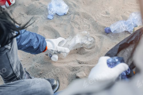 Preview: Cropped imafe of girl picking up plastic trash with group of volunteers on the beach
