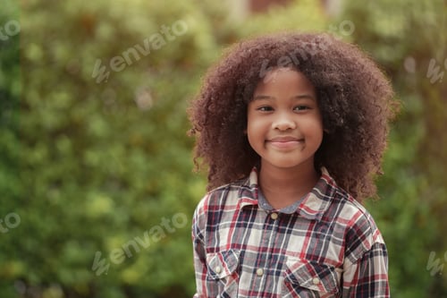 Preview: African American kid girl is smiling in the garden or outdoors.