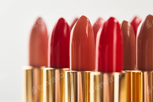 Preview: selective focus of various red shades of lipstick in tubes isolated on grey