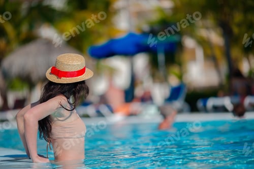 Preview: Beautiful young woman relaxing in swimming pool. Happy girl in outdoor pool at luxury hotel