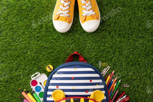 Preview: Top view of back to school supplies with backpack and yellow sneakers placed on green grass