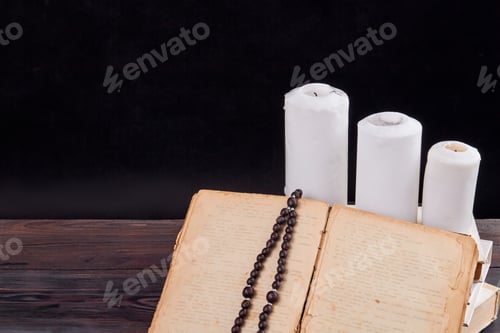 Preview: Old book and candles in a dark room.