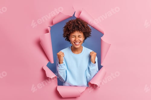 Preview: Happy Young Woman Celebrates Breaking Through Paper Wall
