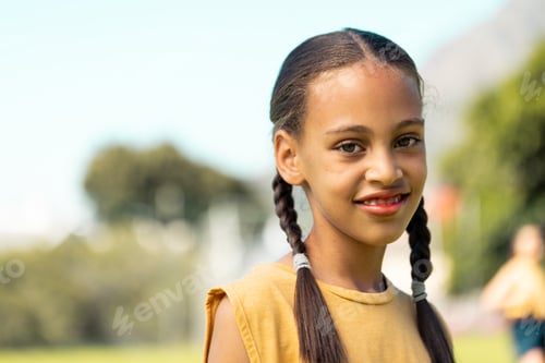 Preview: Portrait of biracial schoolgirl smiling in sports field at elementary school