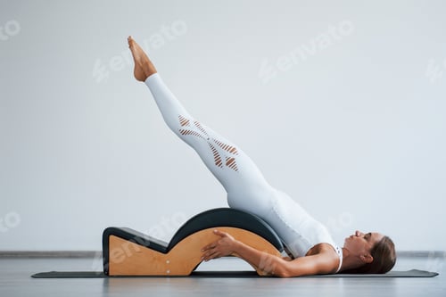 Preview: woman with slim body type in the healthy center doing exercises by using special equipment