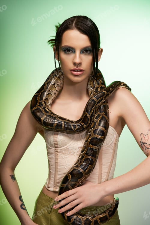 Preview: Young beautiful woman confidently posing with a striking serpent in a vibrant studio setting