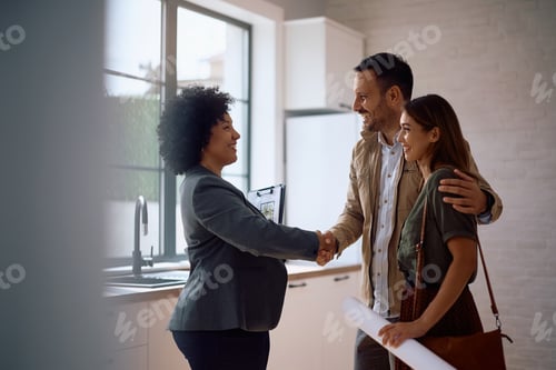 Preview: Happy real estate agent shaking hands with potential new home buyers.