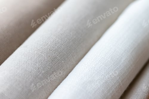 Preview: Diagonal textural background of three types of natural linen fabric, rolled up