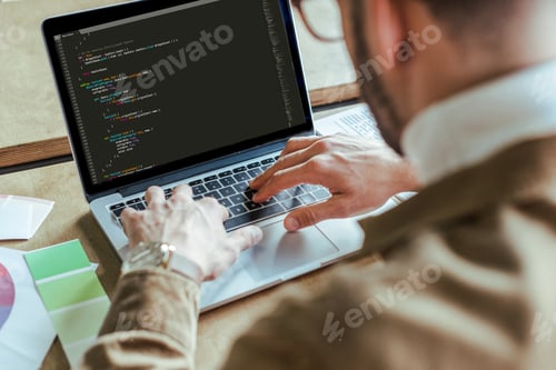 Preview: Cropped view of developer using laptop at table
