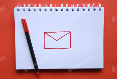 Preview: Overhead photo of a notebook with a drawing of a symbol for email and a pen on red background