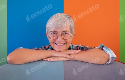 Preview: Portrait of attractive senior woman white hair sitting with crossed arms on the back of the armchair