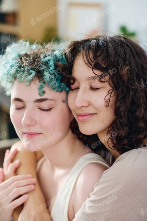 Preview: Happy young woman with dark wavy hair giving hug to her girlfriend