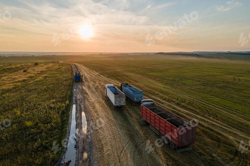 Preview: Aerial view of cargo truck driving on dirt road between agricultural wheat fields