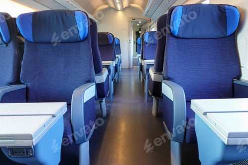 Preview: Empty blue seats with headrests and folding tables inside a sleek high speed train