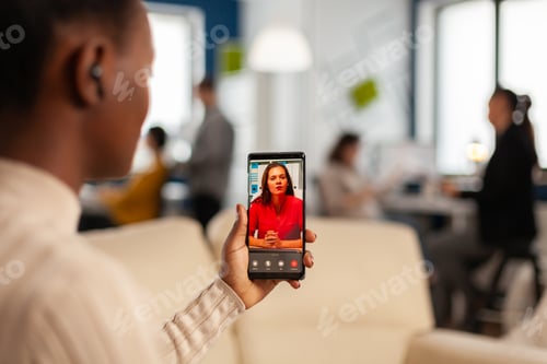 Preview: Over the sholder of black employee discussing with partner on video call