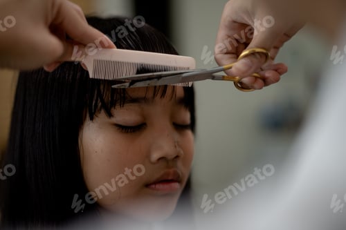 Preview: Asian Mother cutting hair to her daughter in living room at home while stay at home