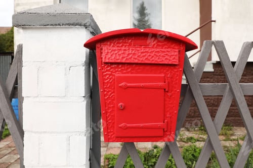 Preview: Beautiful red mailbox on grey fence outdoors