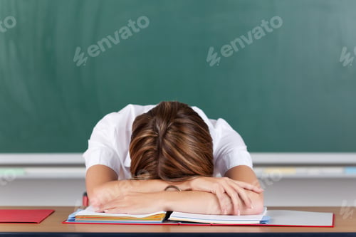 Preview: Teacher Suffering From Acute Stress Resting Her Head On Her Arms At Her Desk In Front Of The