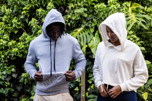 Preview: African american couple wearing white and grey hooded sweatshirts in garden