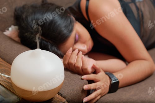 Preview: Young latina woman using aromatherapy to relax. Wellness concept.