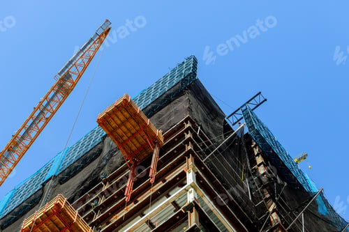 Preview: Construction site with high-rise crane supplies material to a high-rise buildingtwo cranes