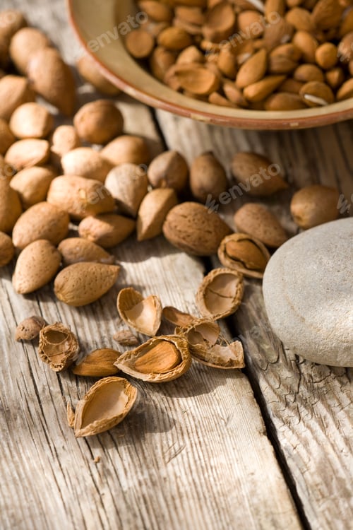 Preview: Bowl of almonds (Prunus dulcis) broken and in nutshells on table