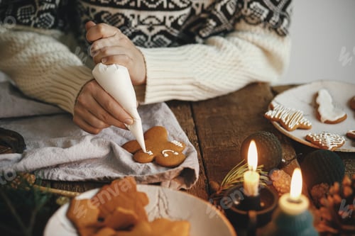 Preview: Decorating christmas gingerbread man cookie with icing on rustic table. Making christmas cookies