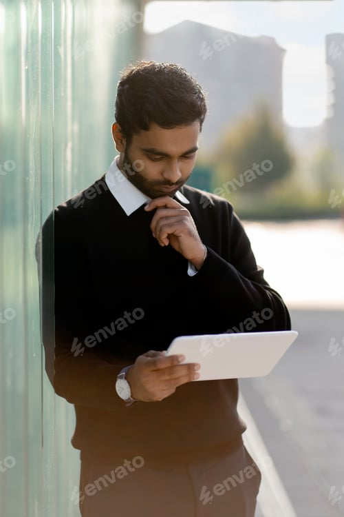 Preview: Indian man using digital tablet on the street