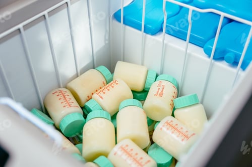 Preview: Plastic bottles with donor breast milk stored inside medical freezer alongside blue ice packs.