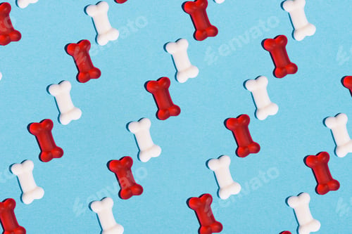 Preview: top view of gummy candies in shape of bones in rows on blue