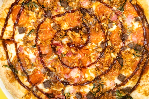 Preview: Delicious large pizza with bacon and spinach on a yellow background
