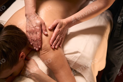 Preview: Wellness center massotherapist giving upper back massage to female