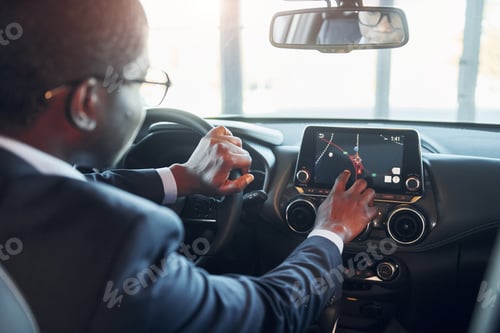 Preview: Vehicle interior. Young african american businessman in black suit is in the automobile