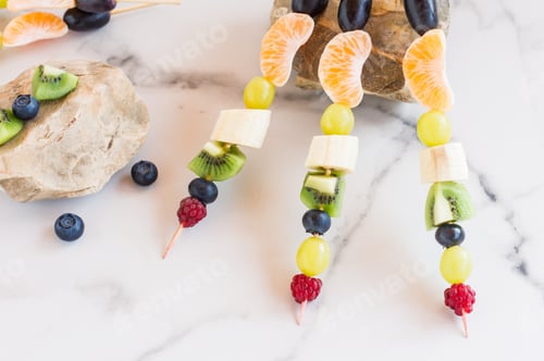 Preview: canapes of juicy fruits and berries on stones, side view.
