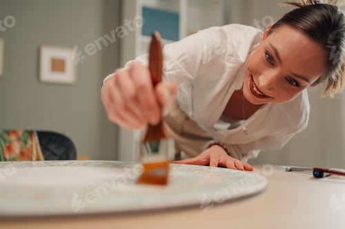 Preview: Smiling woman restoring furniture with varnish and paintbrush