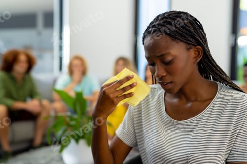Preview: Distressed african american woman holding tissue and crying in group therapy session