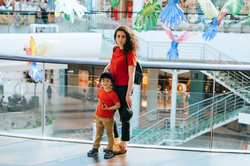 Preview: Young tired woman with son at entertainment center. Little boy spending time with babysitter